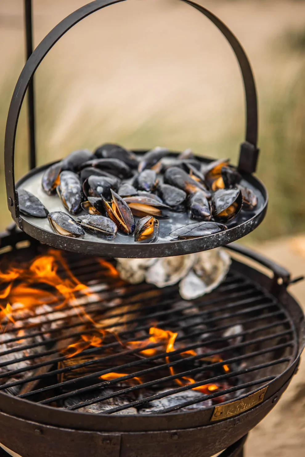 Mussels cooking outdoors over a Kadai fire